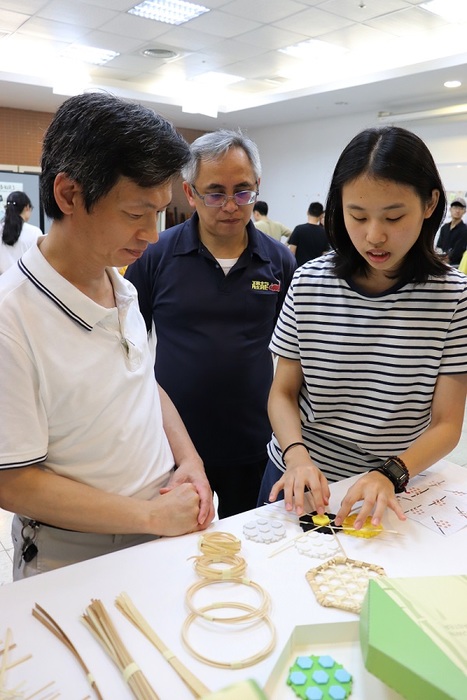 許光宏副校長(圖左)、藝術家瓦利斯哈勇(圖中)聽取工設系同學郭姿儀(圖右)介紹竹編輔助器設計理念。