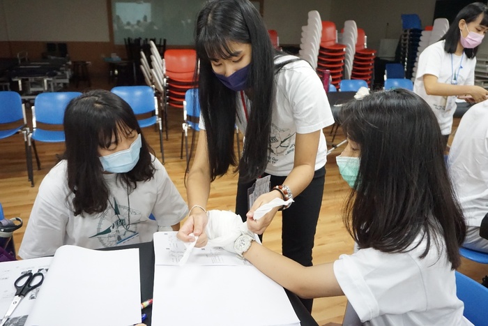 圖為物理治療系學生向高中生示範手部包紮。