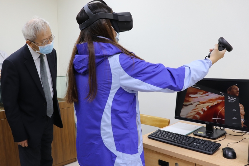 湯明哲校長(圖左)仔細聽取VR針灸教學操作說明。